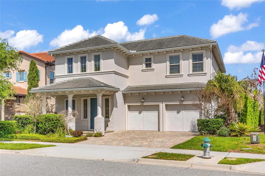 A two-story house with a beige stucco exterior, a tiled roof, and a two-car garage — 15594 SHOREBIRD LANE, WINTER GARDEN, FL