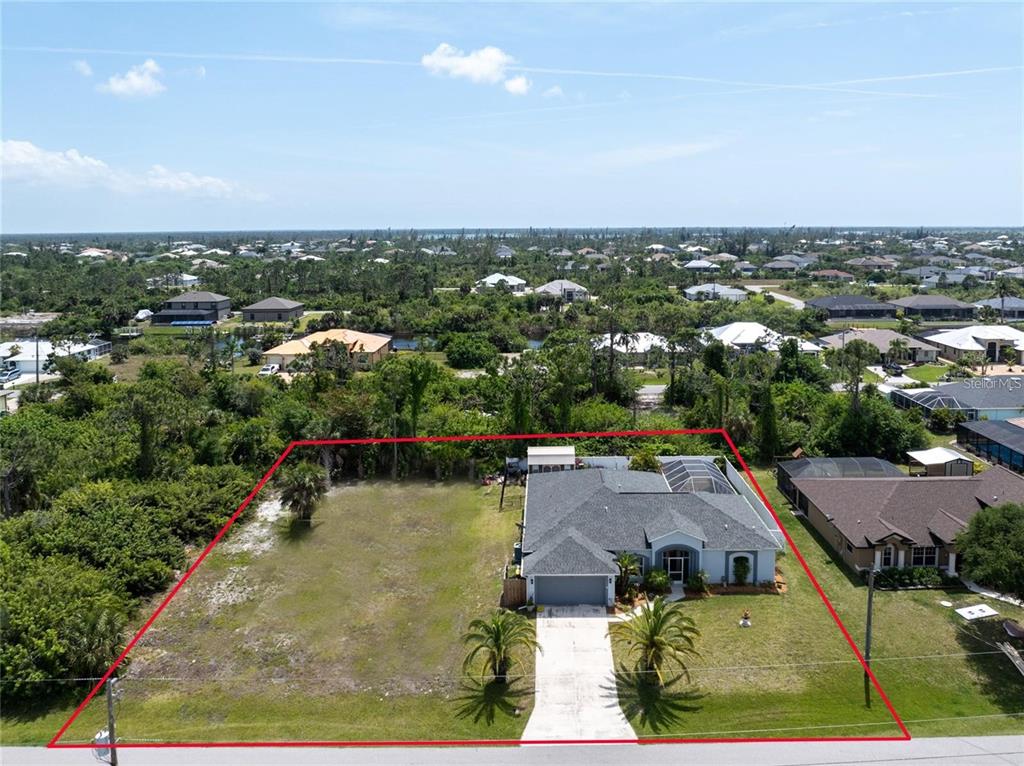 An aerial view shows a single-story house with a large adjacent vacant lot — 15105 ALDAMA CIRCLE, PORT CHARLOTTE, FL