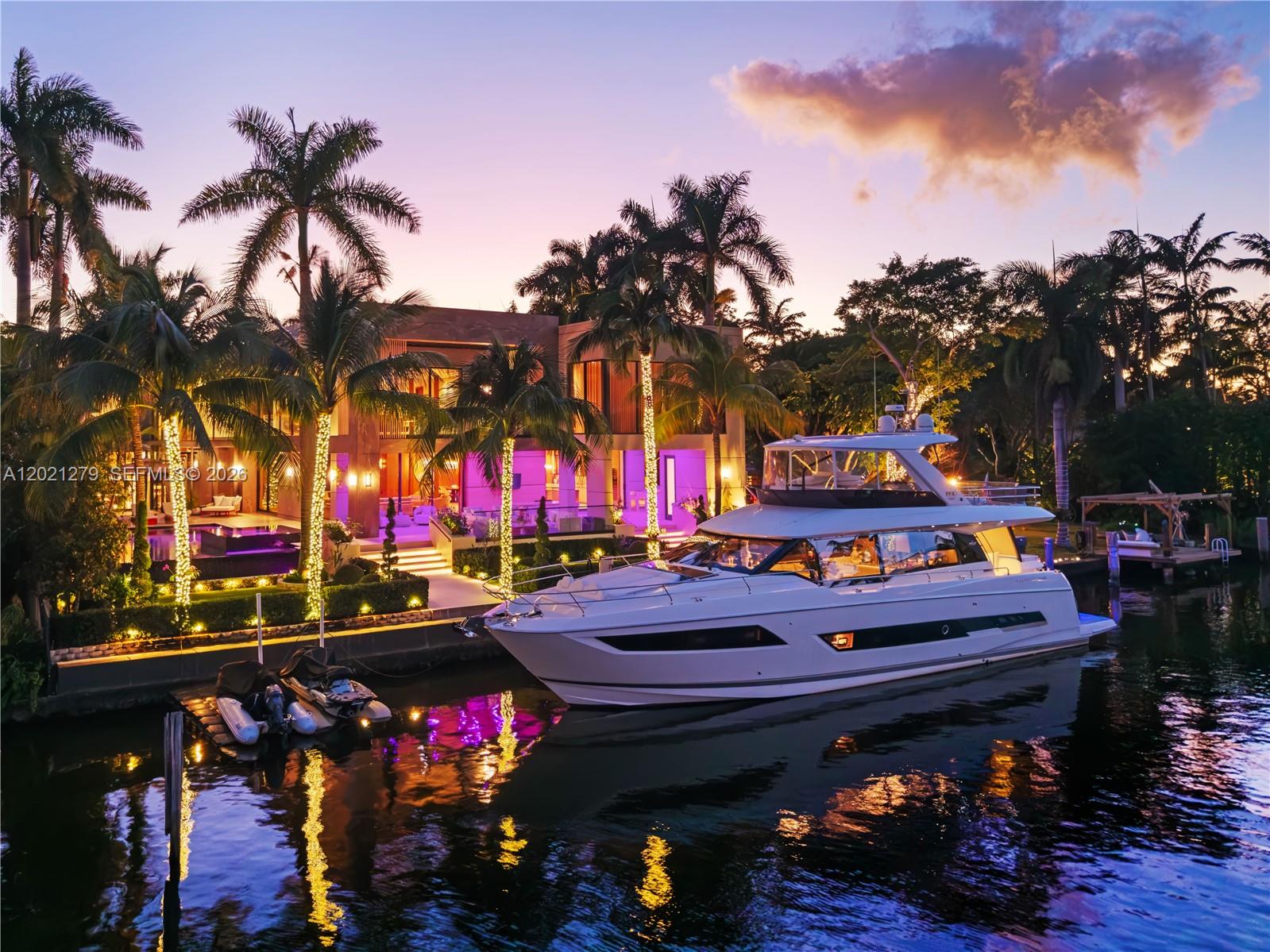 A white yacht is docked in front of a modern house with illuminated palm trees — 905 Belle Meade Island Dr, Miami FL 33138, MIAMI, FL