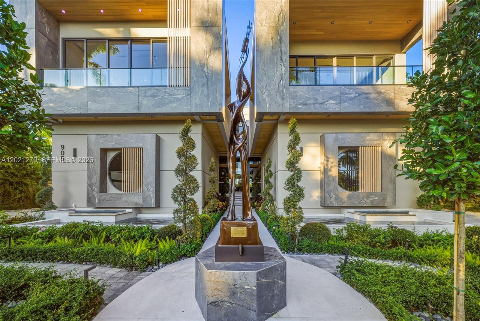 A modern exterior features a tall bronze sculpture centered between two symmetrical stone-clad building wings — 905 Belle Meade Island Dr, Miami FL 33138, MIAMI, FL