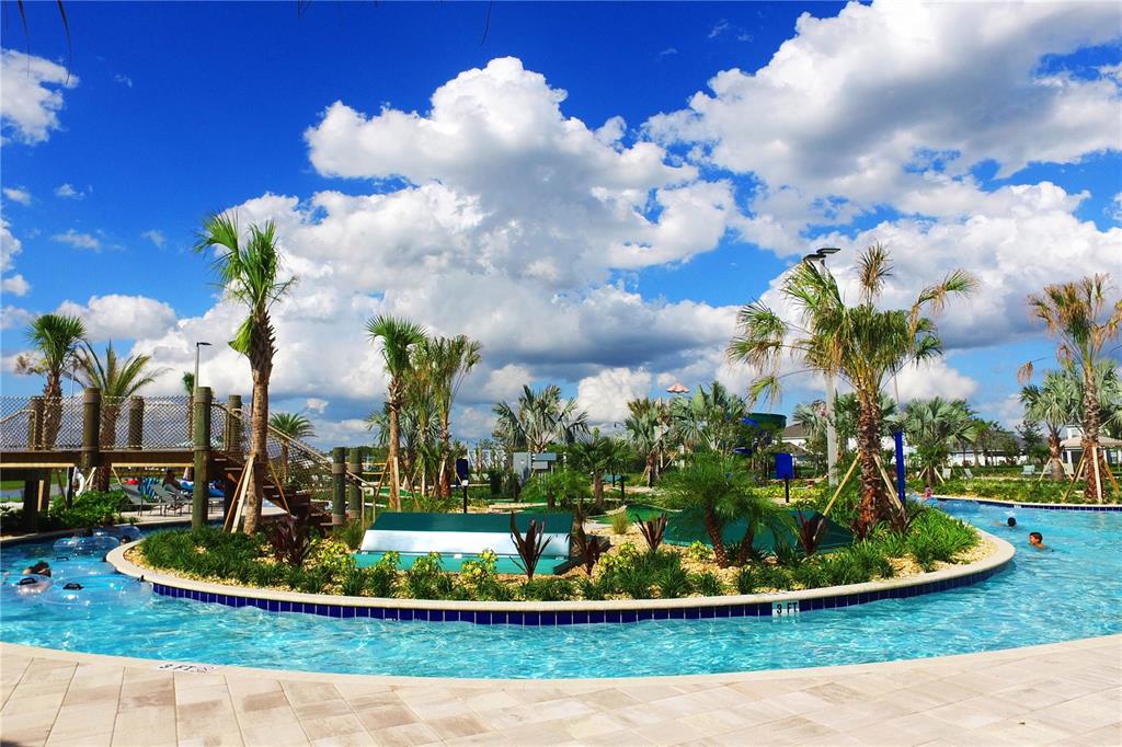 A lazy river winds around a landscaped island with palm trees under a blue sky — 4721 CLOCK TOWER DRIVE UNIT 306, KISSIMMEE, FL