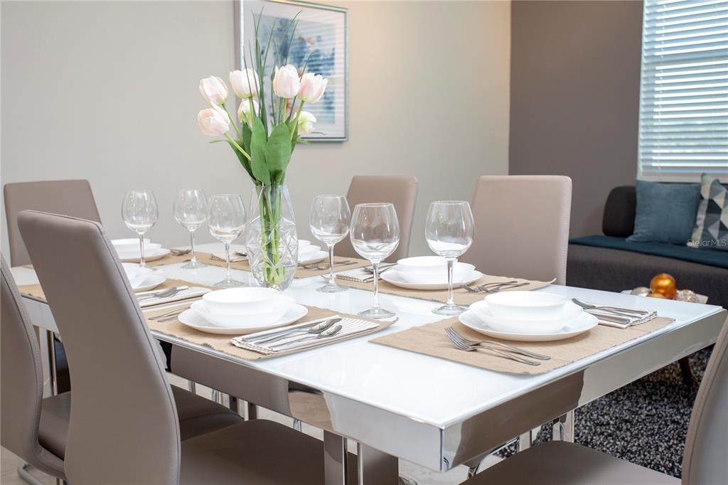 A dining room features a white table set with place settings and a floral centerpiece — 4721 CLOCK TOWER DRIVE UNIT 306, KISSIMMEE, FL