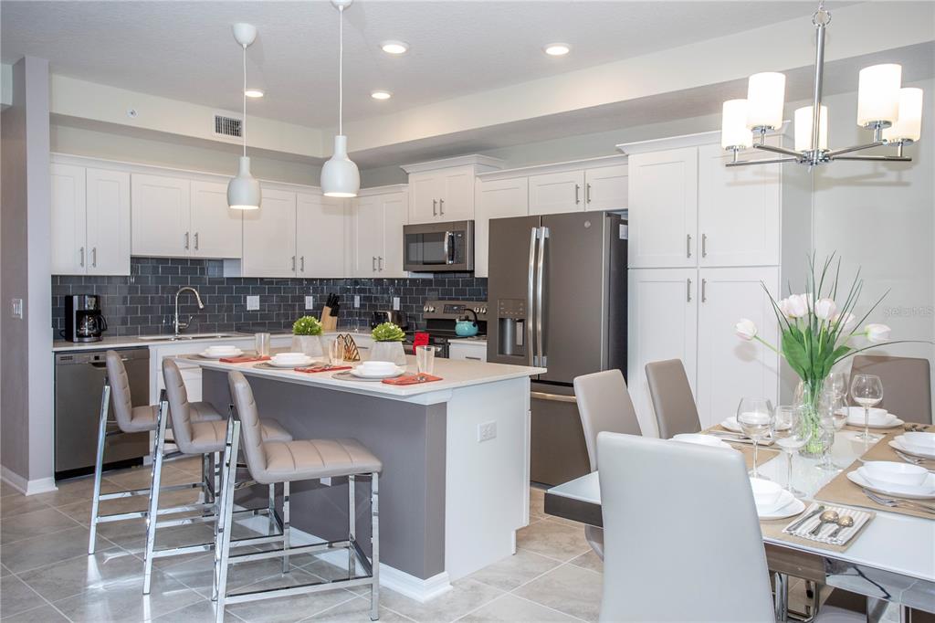 A kitchen with white cabinets, a gray island, stainless steel appliances, and an adjacent dining area — 4721 CLOCK TOWER DRIVE UNIT 306, KISSIMMEE, FL