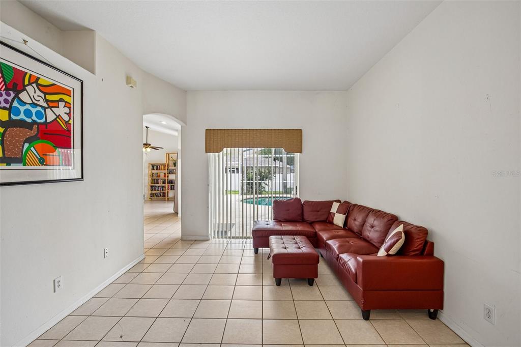 A living room with tile floors, a red sectional sofa, and a sliding glass door — 2302 TOWERING OAKS CIRCLE, SEFFNER, FL