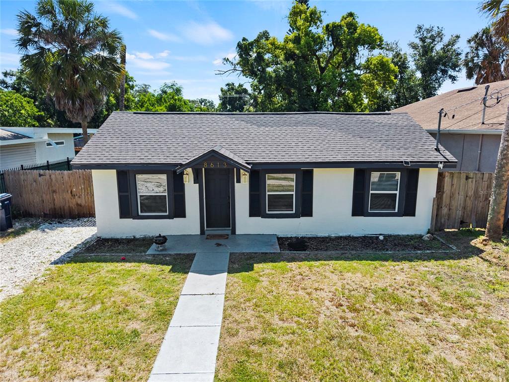 A single-story house with a white exterior, dark shutters, and a gray shingled roof — 8613 N 14TH STREET, TAMPA, FL