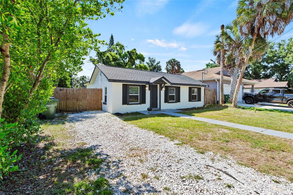 A single-story house with white siding, black shutters, and a gravel driveway — 8613 N 14TH STREET, TAMPA, FL