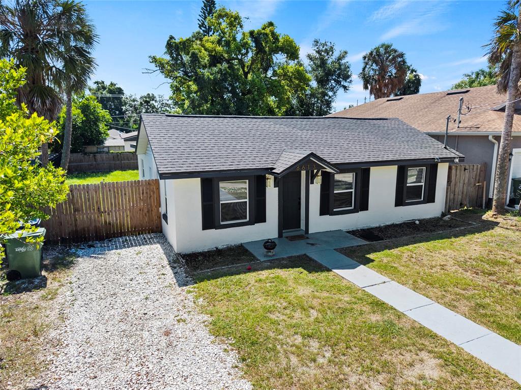 A single-story house with a white exterior, dark shutters, and a gray shingled roof — 8613 N 14TH STREET, TAMPA, FL