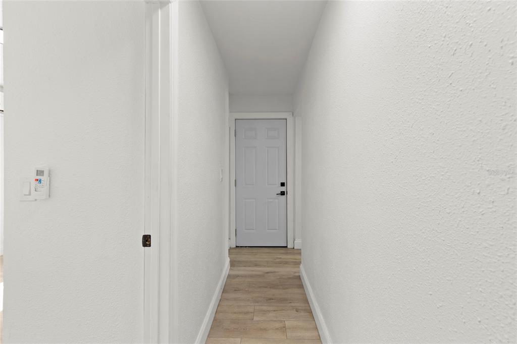 A narrow hallway features white walls, light wood-look flooring, and a white interior door — 8613 N 14TH STREET, TAMPA, FL