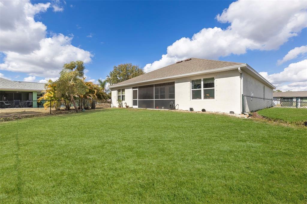 The exterior of a single-story house features a screened-in porch and a large backyard — 25099 BOLIVAR DRIVE, PUNTA GORDA, FL