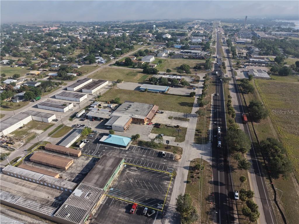 An aerial view shows a commercial property with parking lots and warehouse buildings near a highway — 708 US 27 S, LAKE PLACID, FL