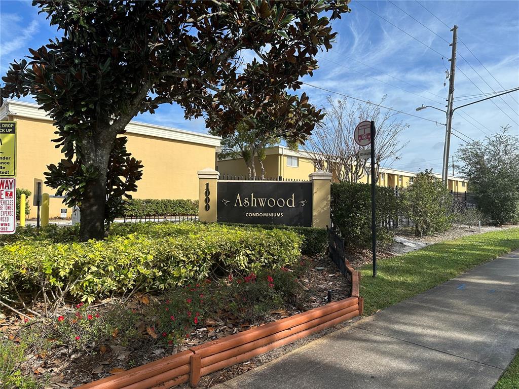 A bedroom features wood-look flooring, a window with blinds, and gray sliding closet doors — 1000 LAKE OF THE WOODS BOULEVARD UNIT 204E, CASSELBERRY, FL