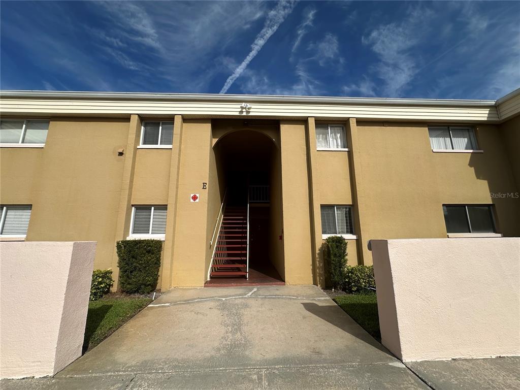 A kitchen features blue lower cabinets, white upper cabinets, stainless steel appliances, and wood flooring — 1000 LAKE OF THE WOODS BOULEVARD UNIT 204E, CASSELBERRY, FL