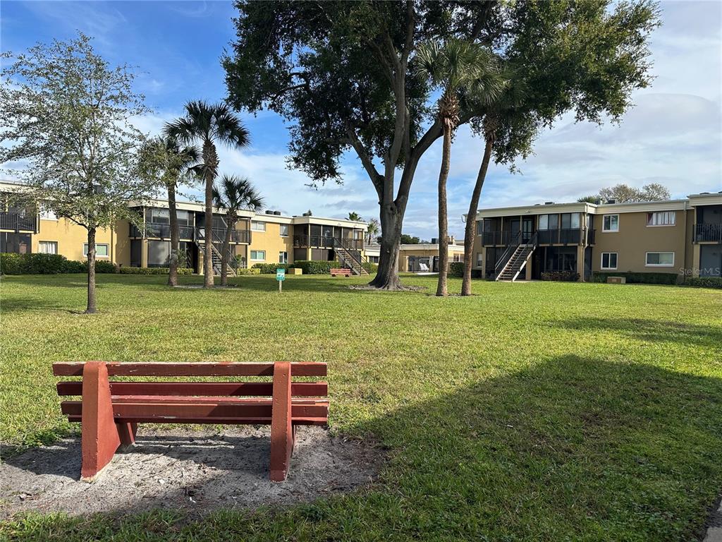 A covered balcony with tiled flooring, black metal railings, and a view of apartment buildings — 1000 LAKE OF THE WOODS BOULEVARD UNIT 204E, CASSELBERRY, FL