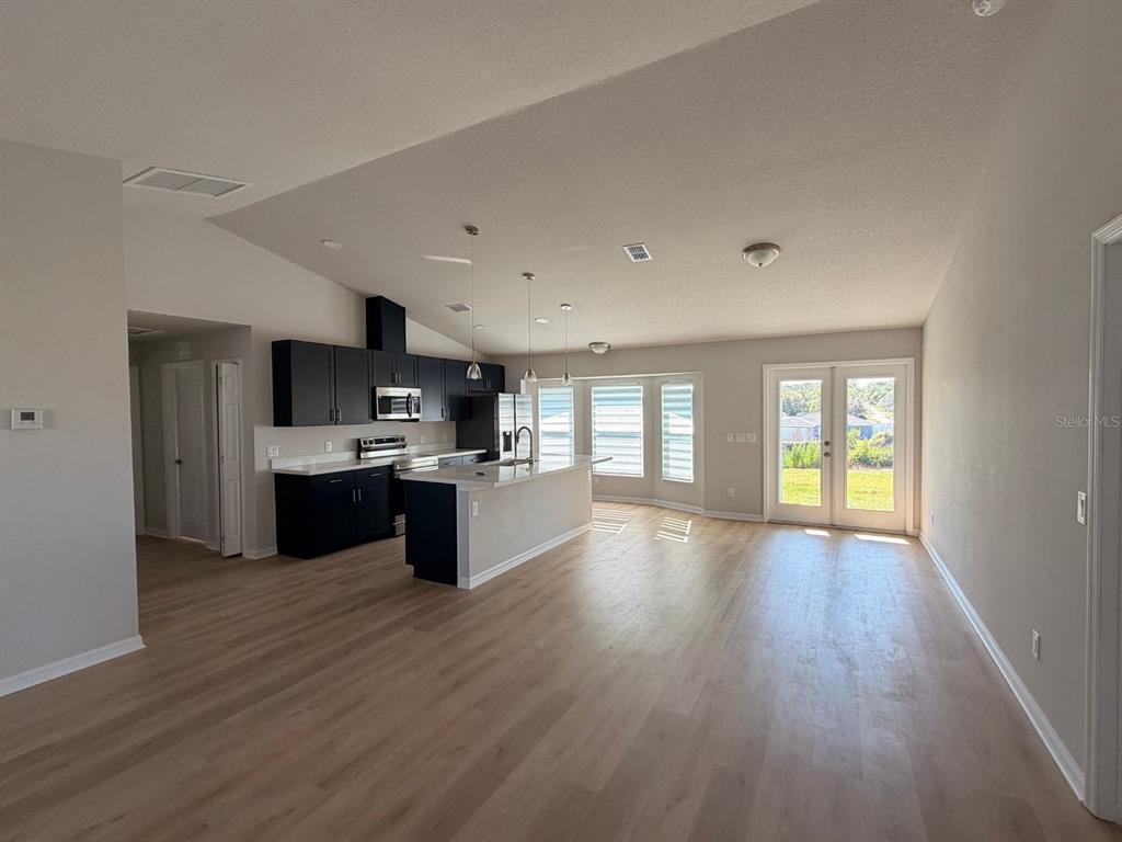 An open-concept kitchen with dark cabinets and a white island overlooks a living area — 110 N DUPONT TERRACE, INVERNESS, FL