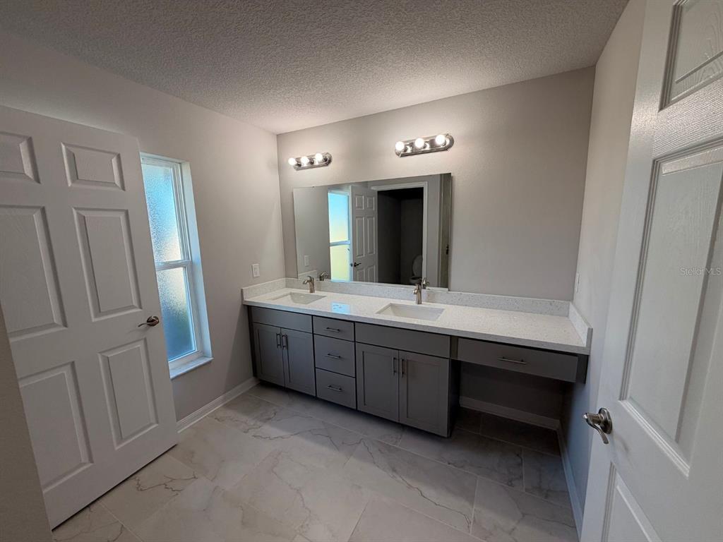 A bathroom features a double vanity with gray cabinets, white countertops, and a large mirror — 110 N DUPONT TERRACE, INVERNESS, FL