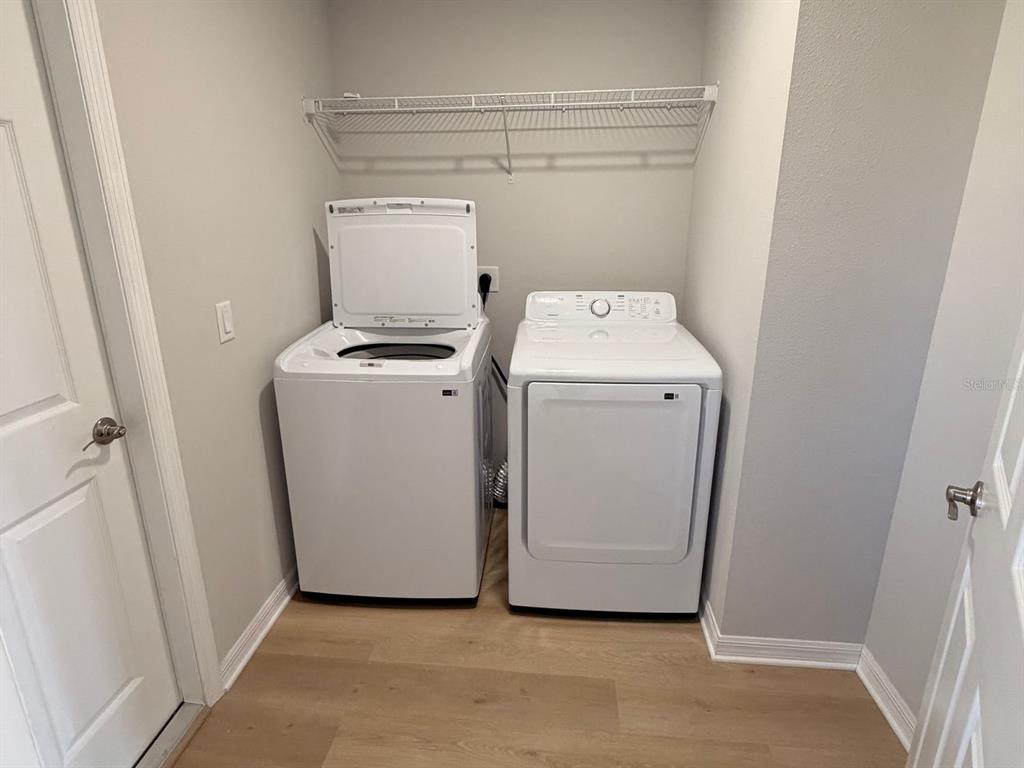 A laundry room features a white top-load washer and dryer beneath a wire shelf — 110 N DUPONT TERRACE, INVERNESS, FL