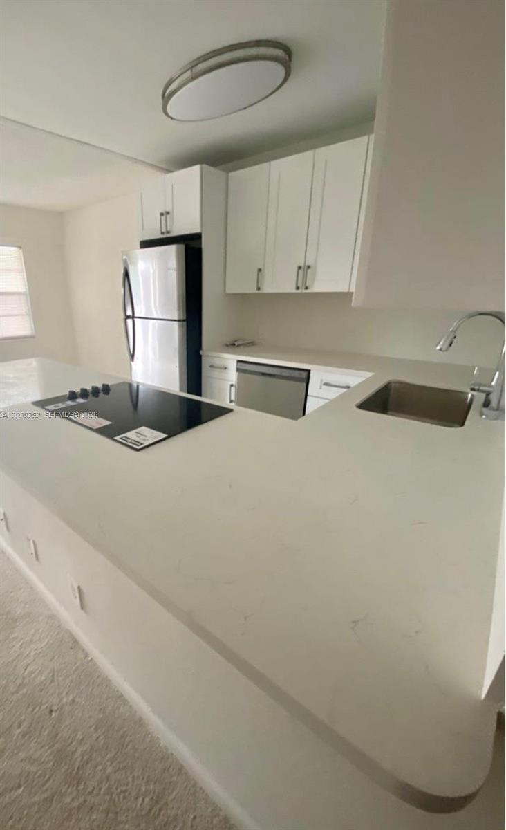 A kitchen features white cabinets, a stainless steel refrigerator, and a white countertop — 335 Brighton H # 335, Boca Raton FL 33434, BOCA RATON, FL