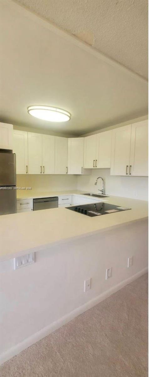 A kitchen features white cabinets, stainless steel appliances, and a peninsula with a cooktop — 335 Brighton H # 335, Boca Raton FL 33434, BOCA RATON, FL