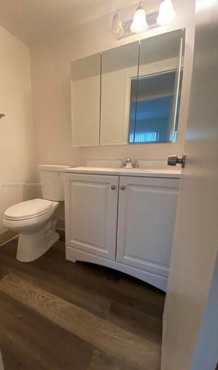 A bathroom features a white vanity, a medicine cabinet, and a toilet on wood-look flooring — 335 Brighton H # 335, Boca Raton FL 33434, BOCA RATON, FL