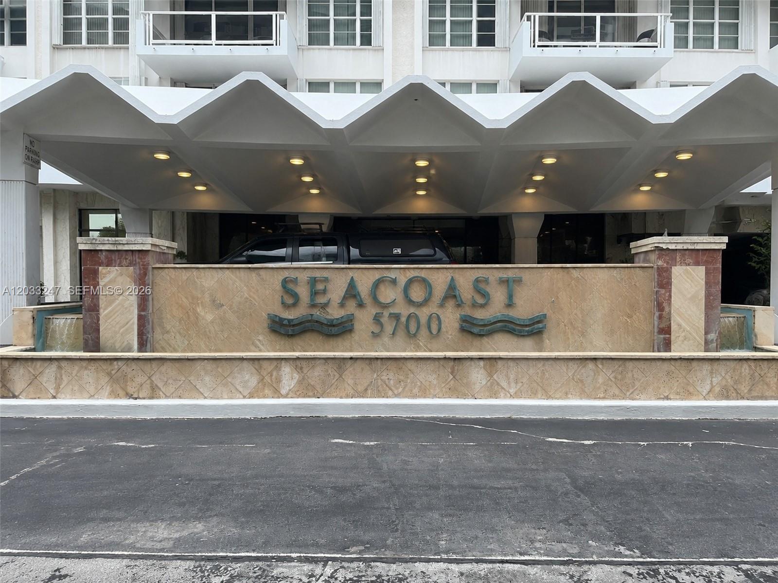 The exterior entrance of a building features a large sign reading Seacoast 5700 — 5700 Collins Ave # 3A, Miami Beach FL 33140, MIAMI BEACH, FL