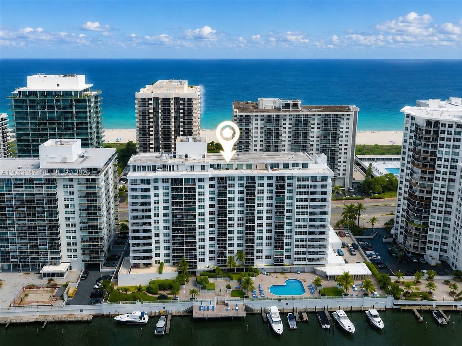 An aerial view shows a white residential building with a pool and boat docks — 5700 Collins Ave # 3A, Miami Beach FL 33140, MIAMI BEACH, FL