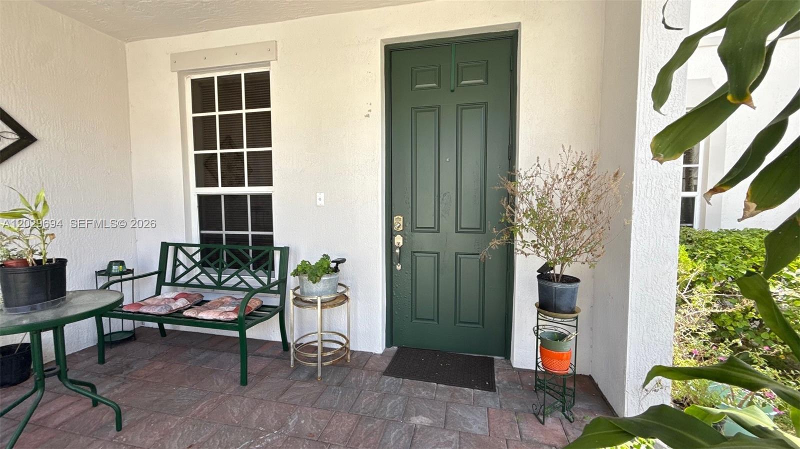 A covered porch features a green door, a matching bench, and several potted plants — 9213 SW 170th Ave, Miami FL 33196, MIAMI, FL