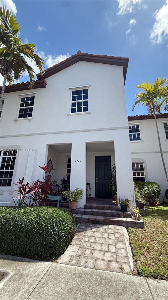 A two-story white stucco townhouse features a dark front door and a paved walkway — 9213 SW 170th Ave, Miami FL 33196, MIAMI, FL