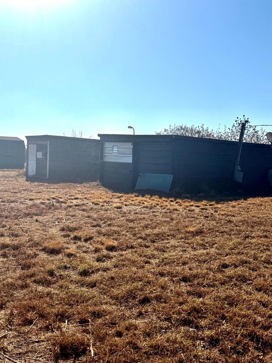 A dark-colored, flat-roofed storage structure sits in a field of dry grass — 3970 NE 80th Avenue, Okeechobee FL 34972, OKEECHOBEE, FL