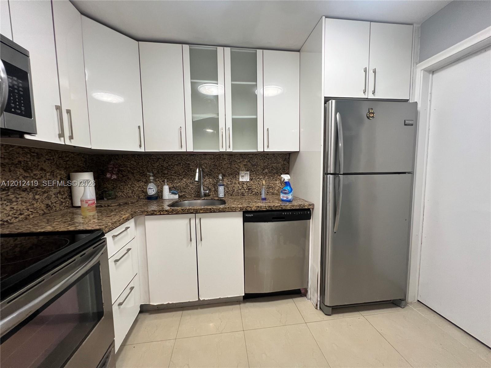 A kitchen features white cabinets, granite countertops, stainless steel appliances, and light-colored tile flooring — 1801 S Ocean Dr # 535, Hallandale Beach FL 33009, HALLANDALE BEACH, FL