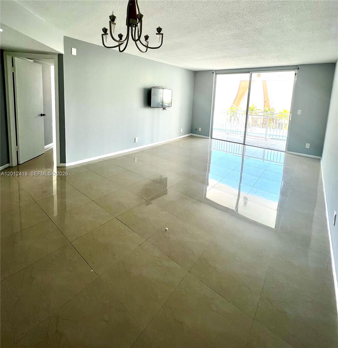 A spacious living room features light gray walls, large beige floor tiles, and a balcony — 1801 S Ocean Dr # 535, Hallandale Beach FL 33009, HALLANDALE BEACH, FL