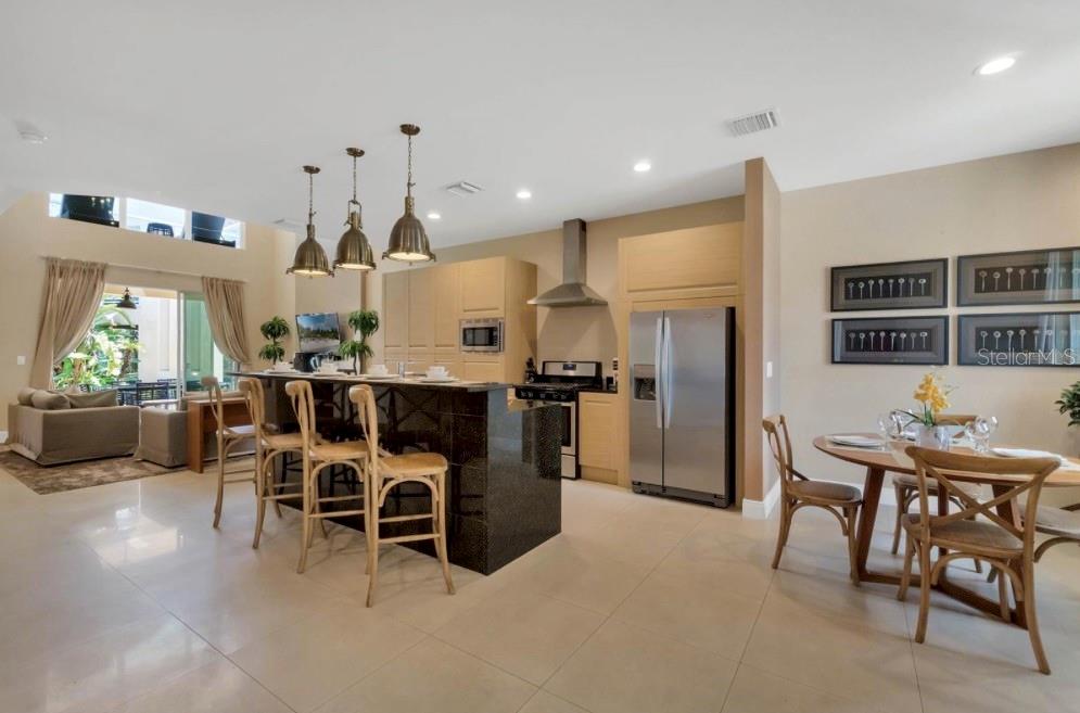 A kitchen with light wood cabinets, a black granite island, and an adjacent dining area — 7651 AMAZONAS STREET, KISSIMMEE, FL
