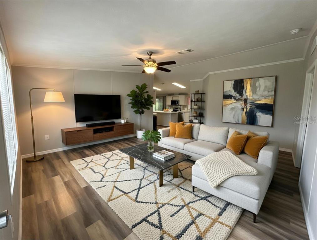 A living room with a sectional sofa, wall-mounted media console, and a patterned area rug — 11922 NW 197TH TER, ALACHUA, FL