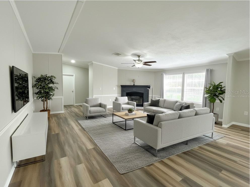 This virtually staged living room features light wood-look flooring, a fireplace, and neutral walls — 11922 NW 197TH TER, ALACHUA, FL