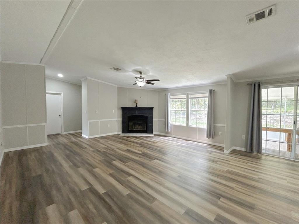 A living room features light wood-look flooring, a black fireplace, and a sliding glass door — 11922 NW 197TH TER, ALACHUA, FL