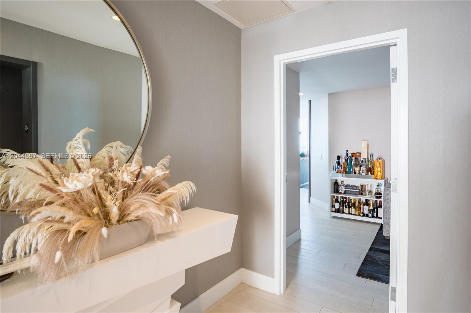 A hallway with a floating shelf and mirror leads to a room with a bar cart — 2900 NE 7th Ave # 4307, Miami FL 33137, MIAMI, FL
