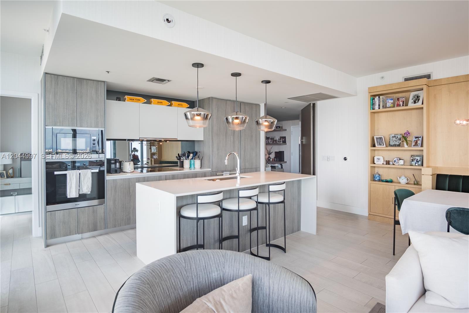A modern kitchen features gray cabinetry, a white island with bar stools, and open shelving — 2900 NE 7th Ave # 4307, Miami FL 33137, MIAMI, FL