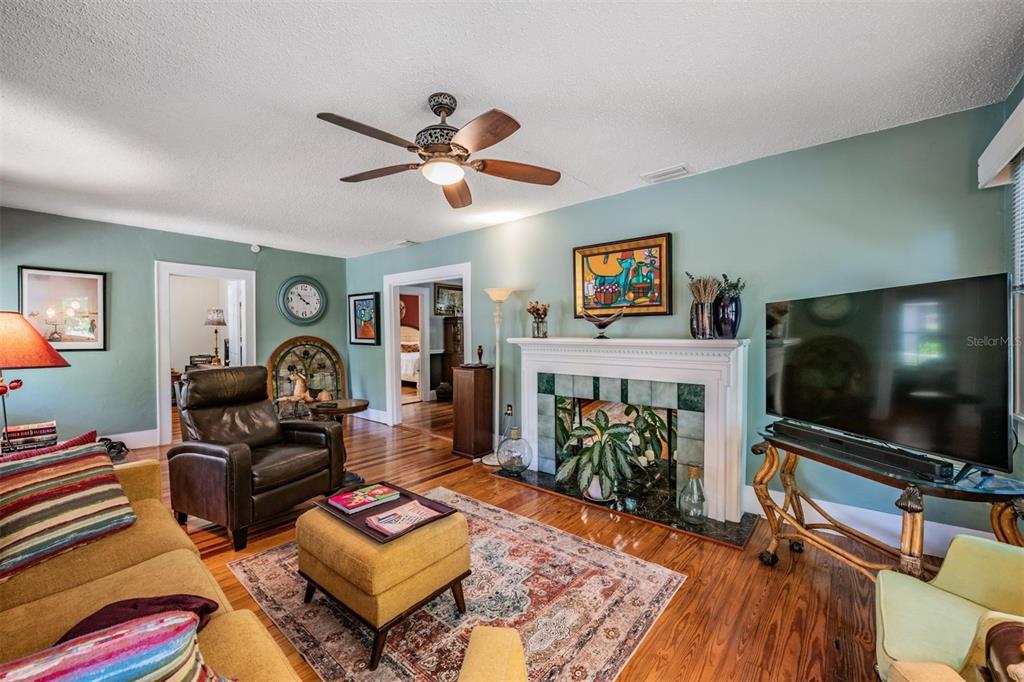 A living room features a fireplace, hardwood floors, a ceiling fan, and a television — 1618 OTTAWA ROAD, CLEARWATER, FL