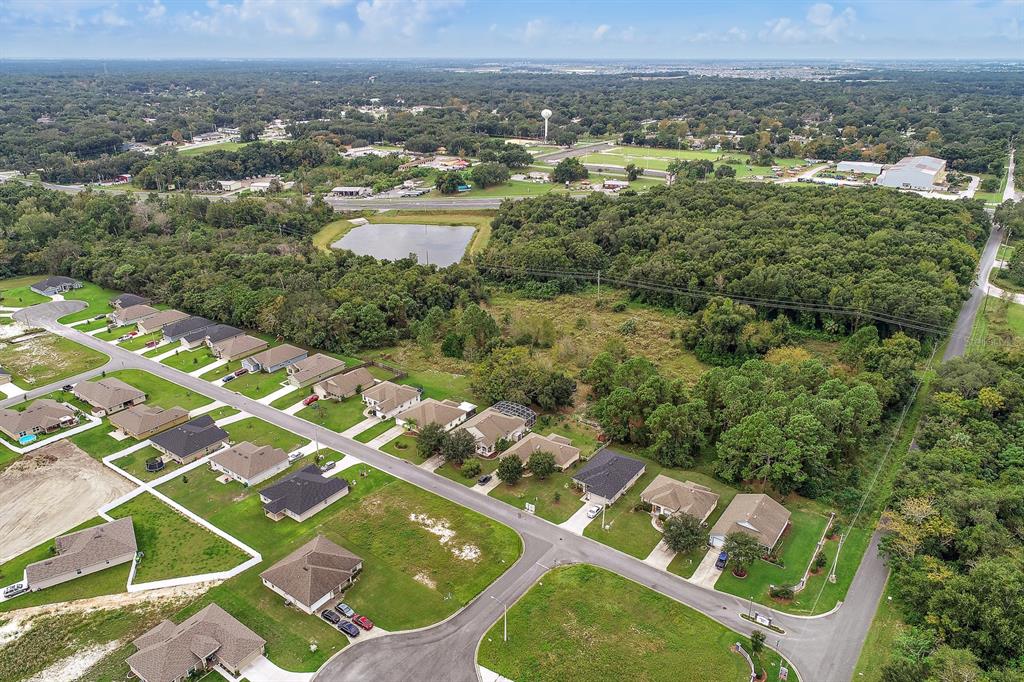 An aerial view shows a suburban neighborhood with single-family homes adjacent to a wooded area — 2631 US-441, FRUITLAND PARK, FL