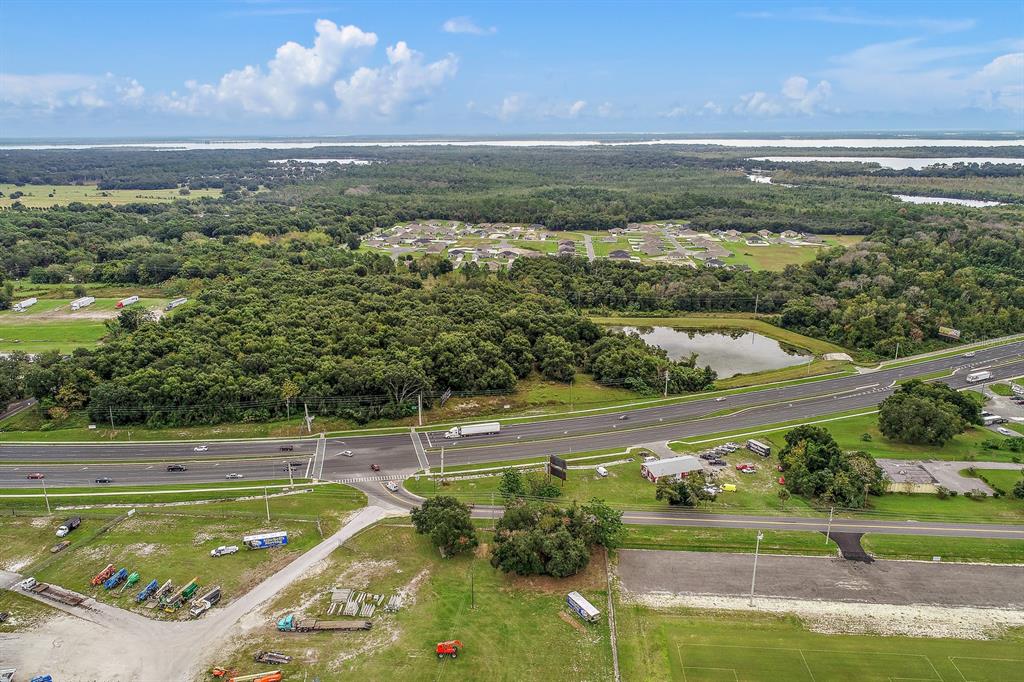 An aerial view shows a highway, a pond, a residential neighborhood, and surrounding wooded land — 2631 US-441, FRUITLAND PARK, FL