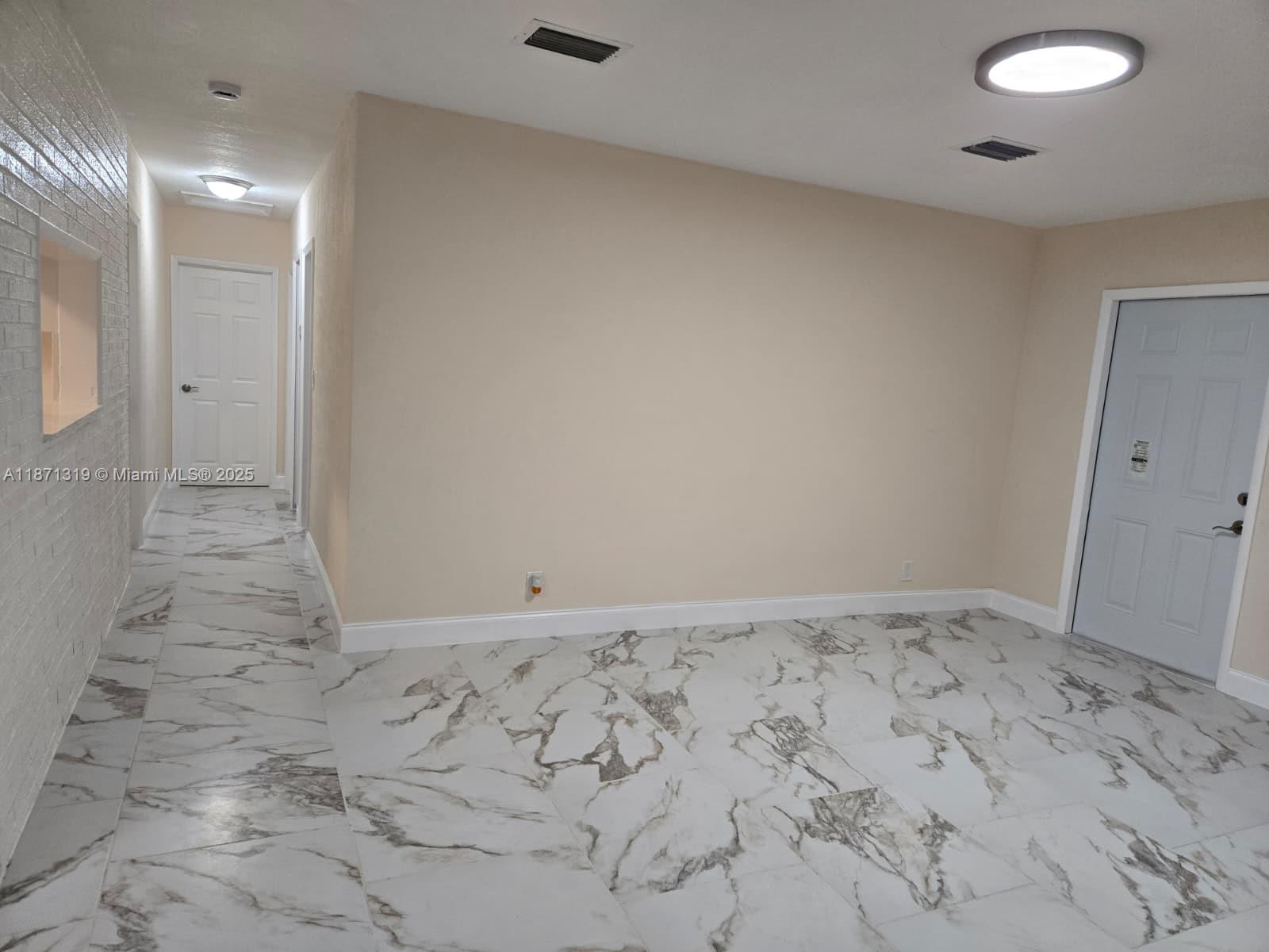 An interior view shows a room with white marble-patterned tile flooring and beige walls — 6751 Meade St, Hollywood FL 33024, HOLLYWOOD, FL