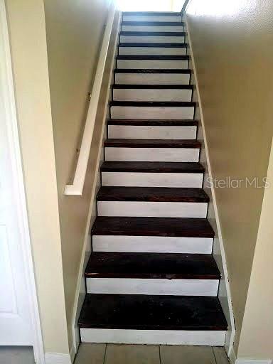 A straight staircase with dark wood treads and white risers leads to an upper level — 4853 ANCHORAGE COVE, PORT RICHEY, FL