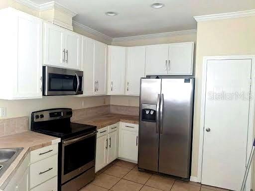 A kitchen features white cabinets, stainless steel appliances, and light-colored countertops — 4853 ANCHORAGE COVE, PORT RICHEY, FL