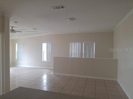 An open-concept living area features light-colored tile flooring, beige walls, and several windows — 4853 ANCHORAGE COVE, PORT RICHEY, FL