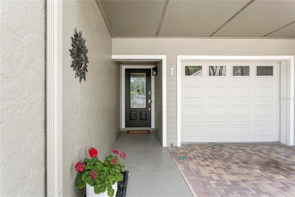 A covered entryway features a dark front door, a white garage door, and a potted plant — 360 PINELLAS BAYWAY S UNIT I, TIERRA VERDE, FL