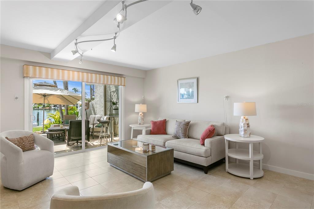 A living room with tile floors, a sofa, two armchairs, and a sliding door to a patio — 360 PINELLAS BAYWAY S UNIT I, TIERRA VERDE, FL