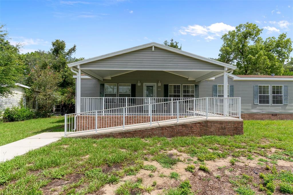 A single-story manufactured home with a covered front porch and a wheelchair-accessible ramp — 7351 W HADENOTTER LANE, HOMOSASSA, FL
