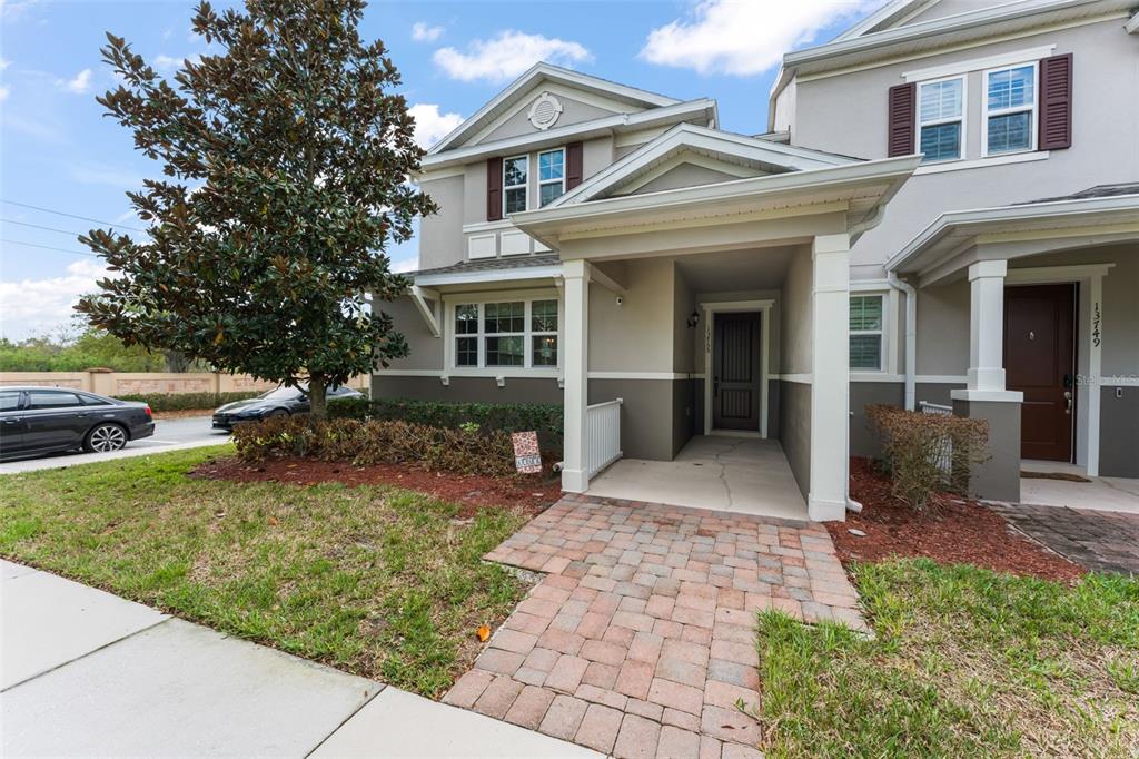 A two-story townhouse exterior features a brick walkway leading to a covered front entrance — 13755 BRAVANTE ALLEY, WINDERMERE, FL