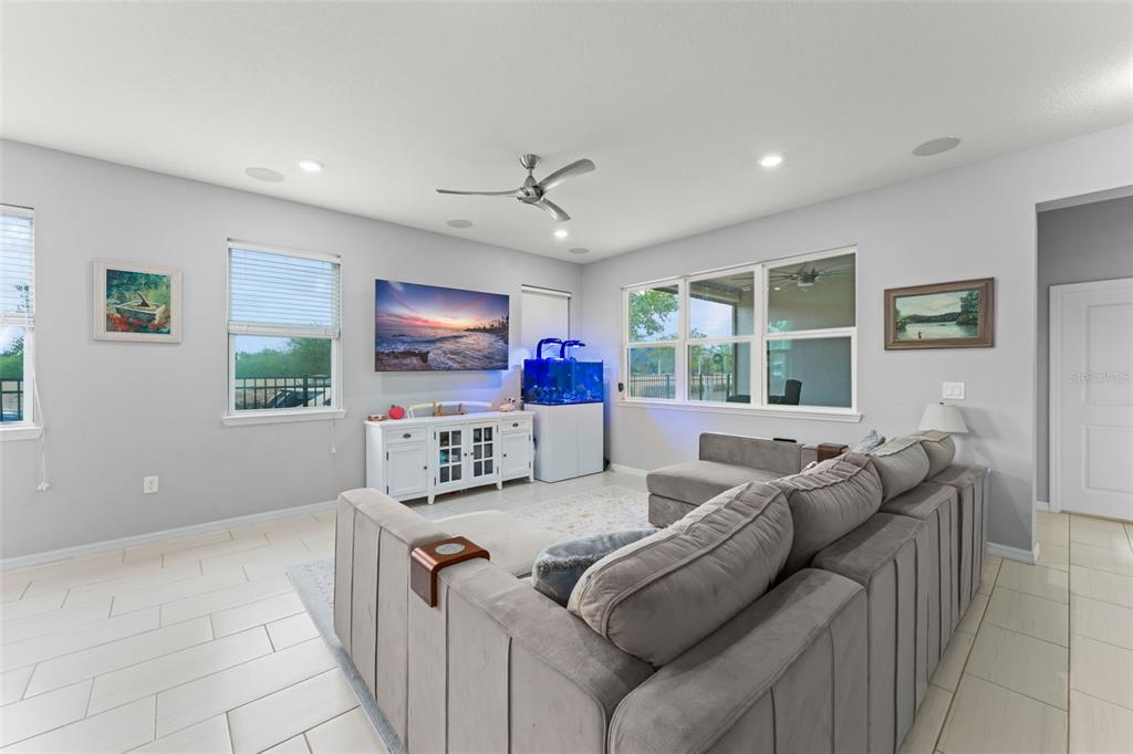 A living room features a grey sectional sofa, a television, and a fish tank — 13755 BRAVANTE ALLEY, WINDERMERE, FL