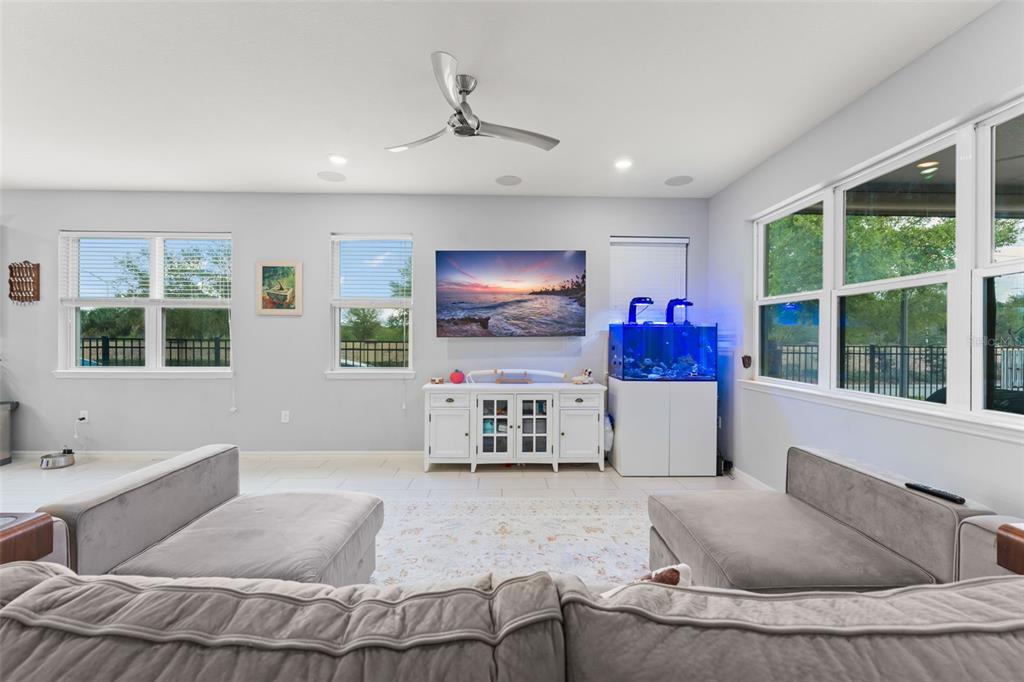 A living room features a wall-mounted television, a white media console, and a fish tank — 13755 BRAVANTE ALLEY, WINDERMERE, FL
