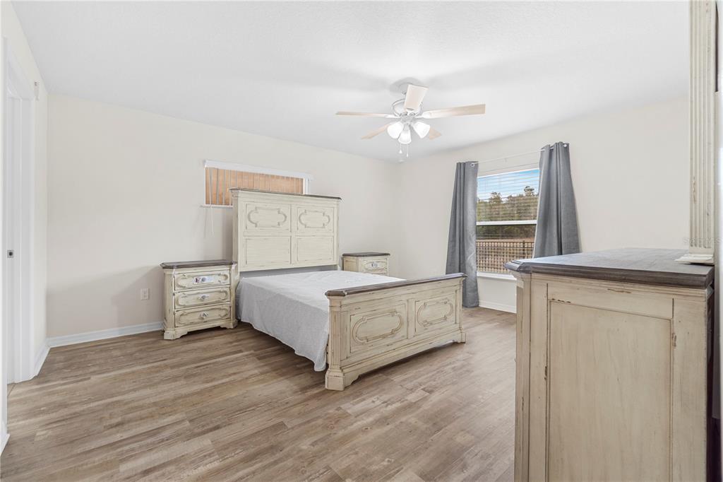 A bedroom with light-colored wood-look flooring, a white bed frame, and a ceiling fan — 3321 SW 153RD PLACE ROAD, OCALA, FL